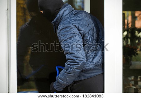 A burglar entering a house through an open window