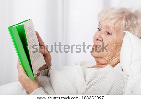 Elderly lady during reading book in bed