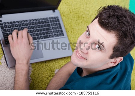 Happy man with laptop laying on the floor