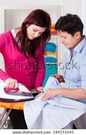 Mum and her daughter during ironing shirt