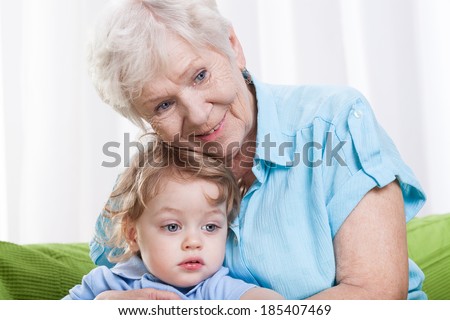 Smiling grandma hugging her little grandson indoors