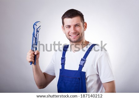 Young smiley repairman holding wrench in hand Young smiley repairman holding wrench in hand