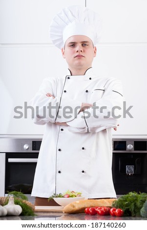 Self-confident young cook posing with arms crossed