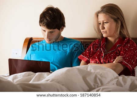 A man surfing the internet in bed in the evening