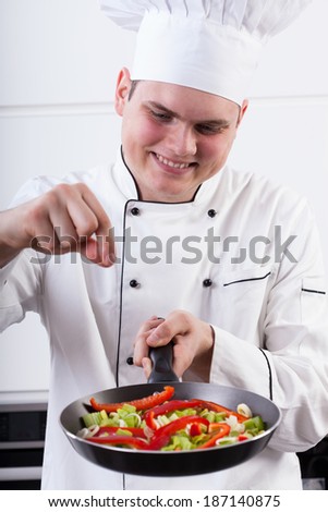 Man adding spices into vegetables in a pan