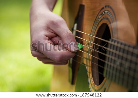 A green guitar pick in a musician\'s hand