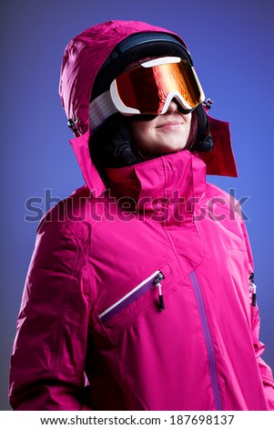 A woman in a pink winter jacket, goggles and a helmet