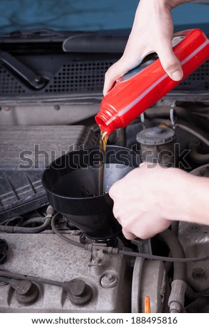 Mechanic during pouring motor oil in garage
