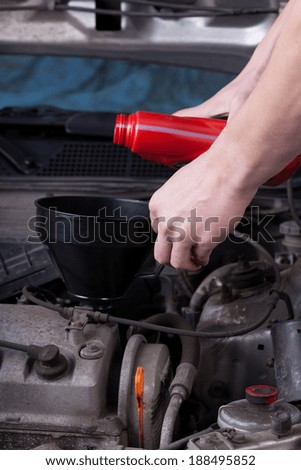 Mechanic during pouring oil into car engine