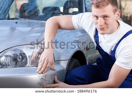 Handsome mechanic during repairing car scratching, horizontal