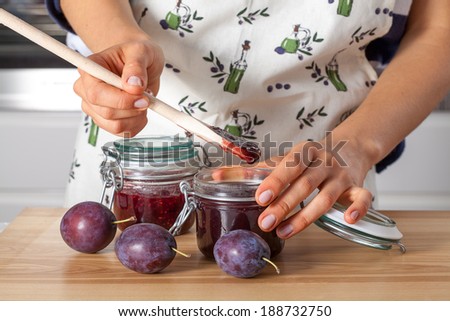 Woman in kitchen preserving a juicy plums