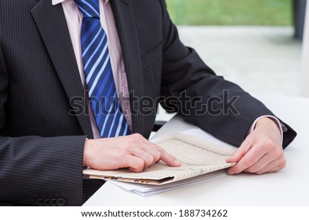 A smartly dressed businessman reading his daily newspaper