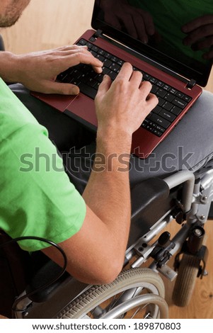 Disabled man in wheelchair typing on laptop