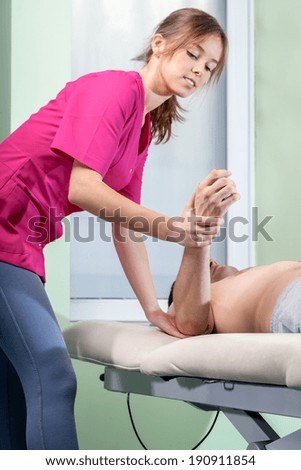 Young female physiotherapist treating tennis elbow, vertical