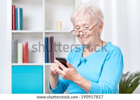 Smiley senior woman texting on mobile phone