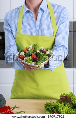 Person holding fresh greece salad with olives
