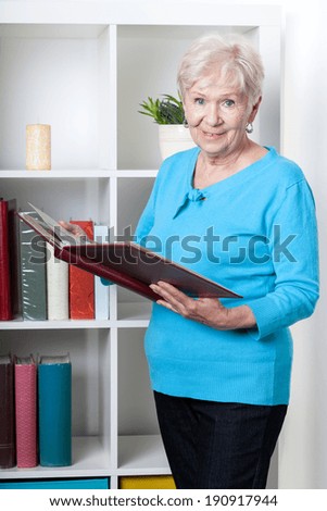 Smiley senior woman viewing family photo album