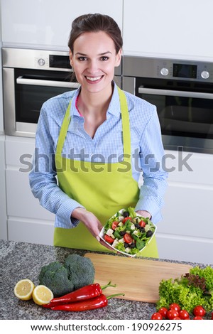 Woman in the white kitchen with fresh salad