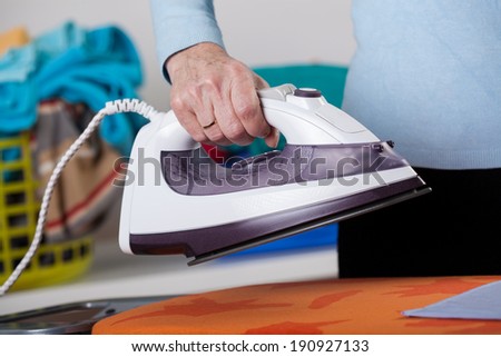 A closeup of a housewife holding a hot iron