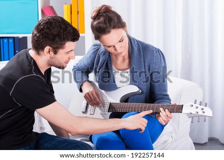 Musician teaching his girlfriend playing electric guitar on a date