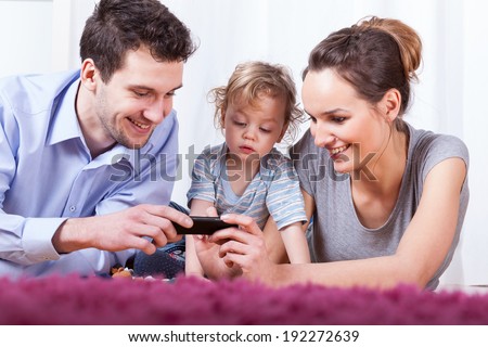 Young parents and their baby having their happy time lying on the floor