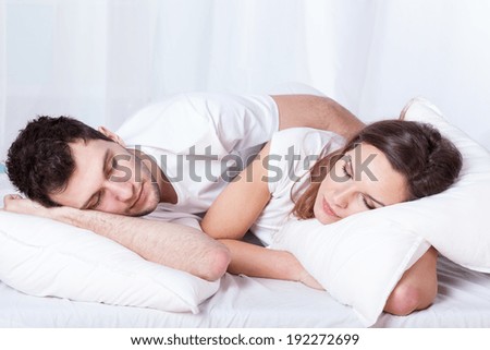 A pretty woman and a handsome man sleeping calmly in bed