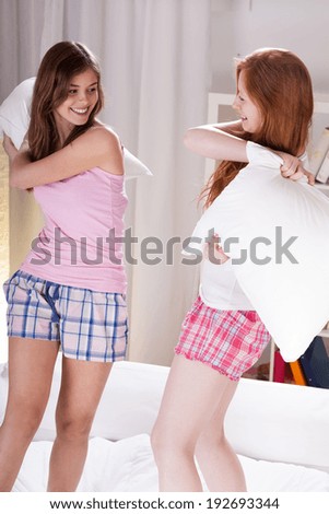 Young teenage girls fighting with pillows in bed
