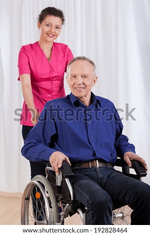 Happy man sitting on wheelchair and his nurse