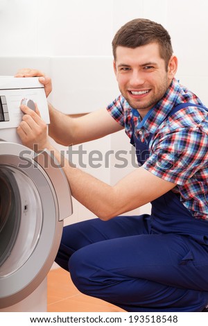 Portrait of a young plumber repairing washing machine
