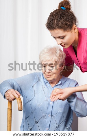 Nurse helping elderly woman get up, vertical