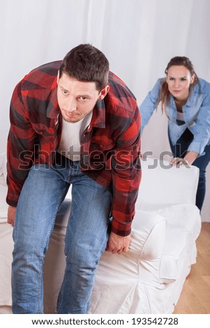 Young couple moving the couch in new flat
