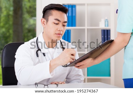 Horizontal view of an asian doctor signing document