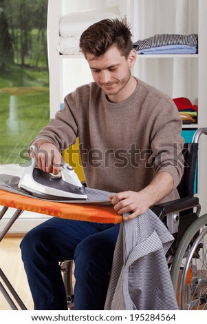 Happy disabled man during ironing shirt, vertical
