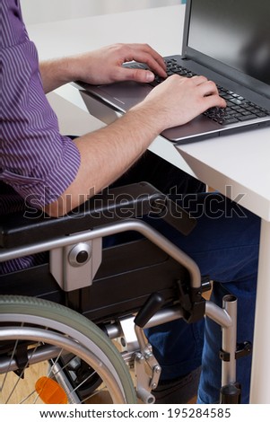 Man on wheelchair working on laptop, vertical