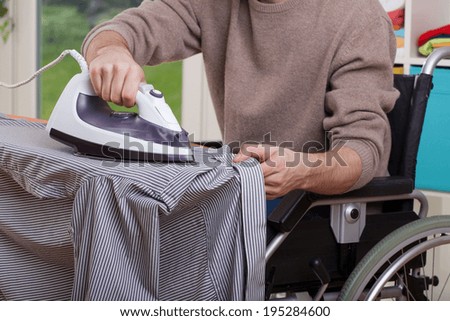 Disabled man during ironing his shirt, horizontal