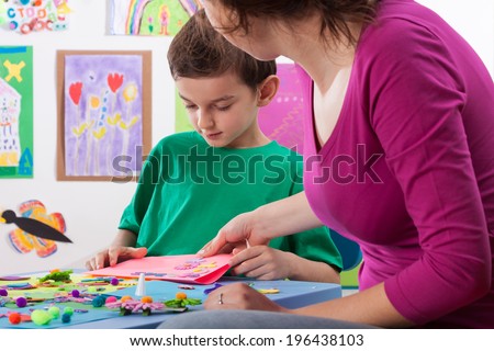 The teacher checks the artwork in the school