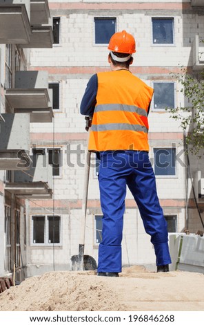 Builder with spade looking at construction, vertical
