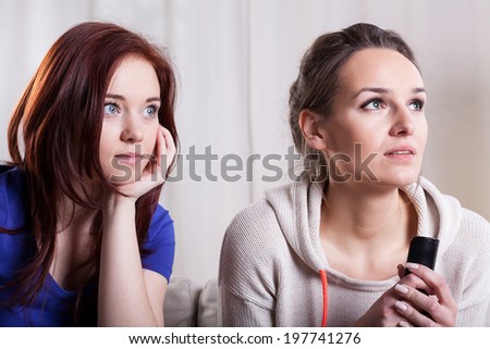 Close-up of two scared women watching television