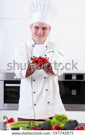 A smiling chef holding fresh and healthy vegetables