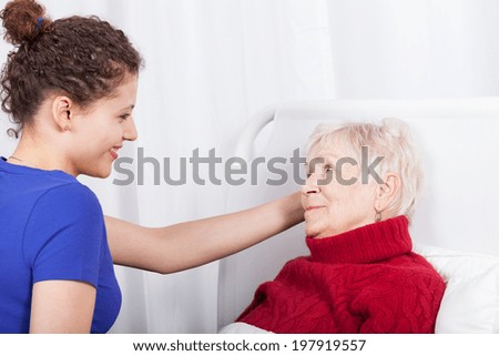 Happy nurse helping an elderly woman in hospital