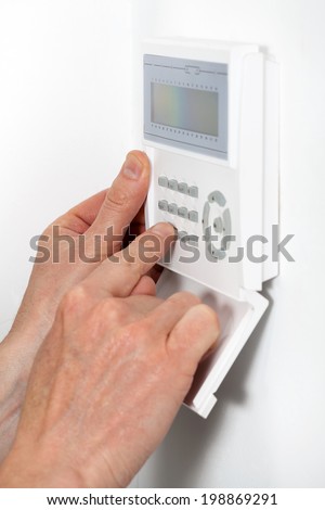 Hands entering a code to burglar alarm
