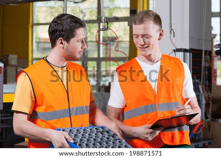 Factory workers in orange protective vest during work