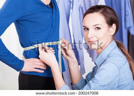 Tailor measuring a woman model in a blue shirt
