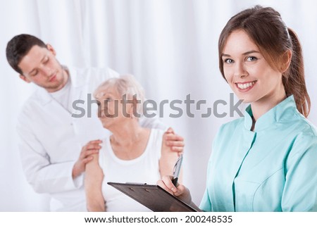 Elderly woman with doctors during rehabilitation, horizontal