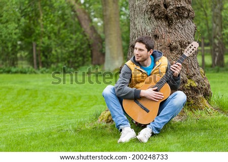 Horizontal view of a man with guitar in garden