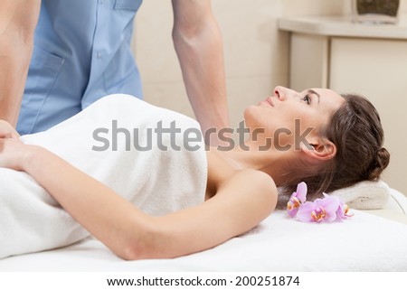 Beautiful woman wrapped in white towel lying on massage table at spa salon