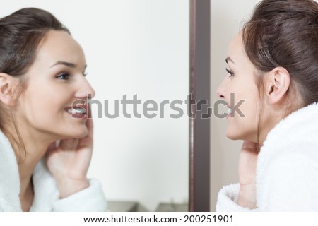 Young woman watching in mirror her skin condition after treatments