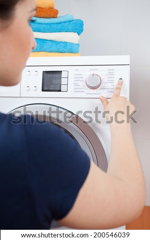 Housekeeper turning on the washing machine, vertical
