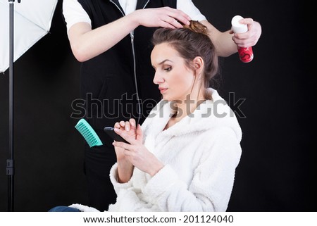Hairdresser applying spray on fashion model\'s hair