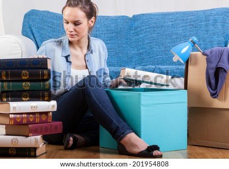 Young attractive student packing books to change flat